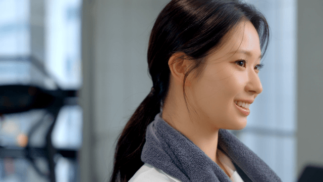 Smiling woman with a towel around her neck at gym