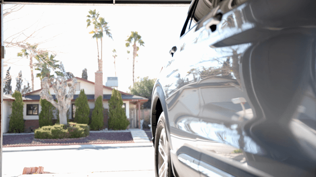 Car exiting a garage into a sunny street