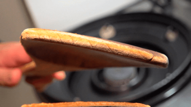 Chef holding old wooden spatula in front of kitchen stove