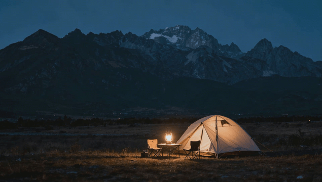 Tent lit at night beneath high terrain