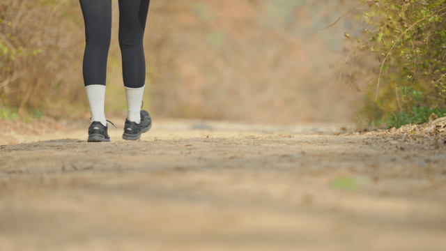 Woman walking on forest trail in leggings hiking outfit