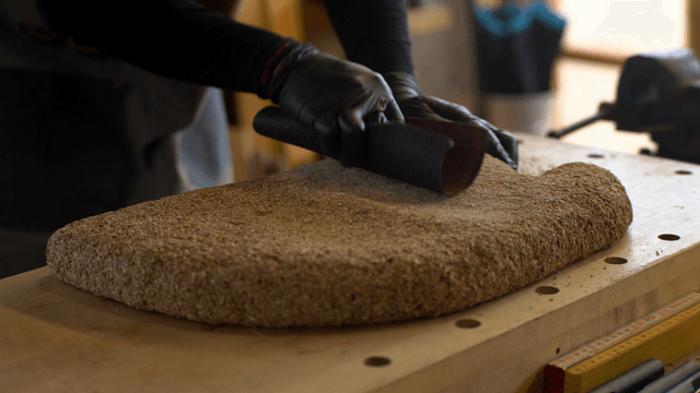 Artisan sanding a cork sculpture with a long sandpaper surface