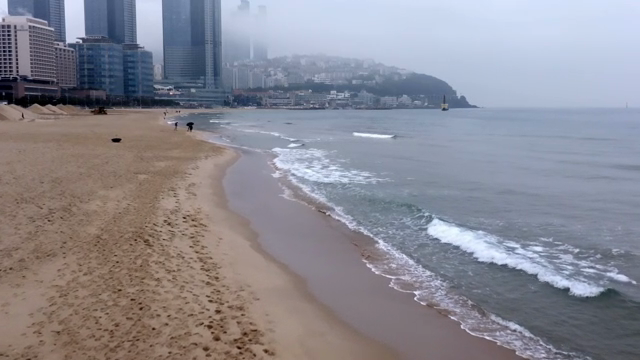 A cloudy day at a city beach with skyscrapers