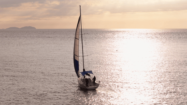 일몰에 잔잔한 바다를 항해하는 요트