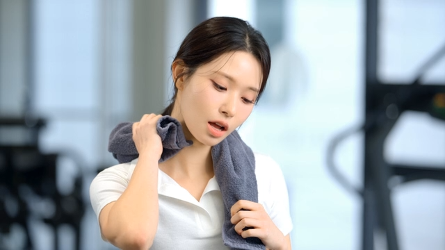 Young woman wiping sweat with a towel at gym