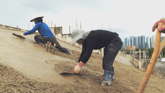 Workers smoothing concrete on a slope