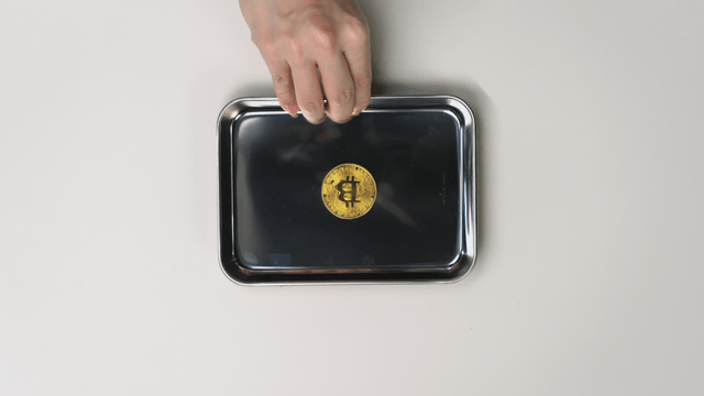 Hand offering a tray with a Bitcoin on it