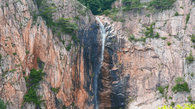 High waterfall flowing along rocky cliff