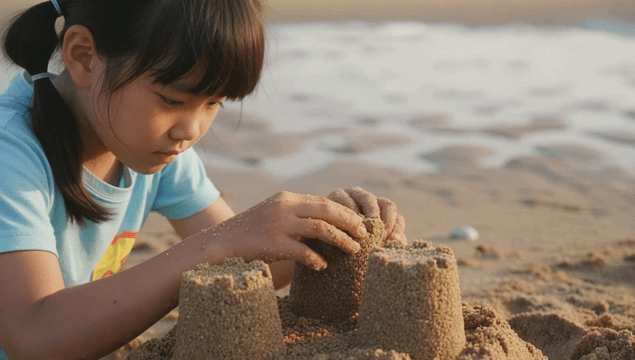 Girl building sandcastle on beach