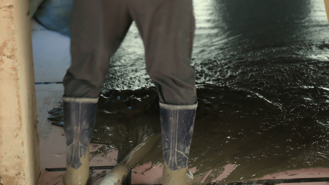 Worker smoothing wet concrete indoors
