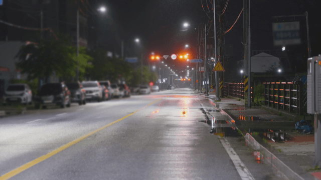 Quiet wet road at night with parked cars