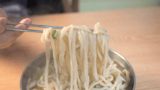 Steaming handmade noodle soup in stainless pot
