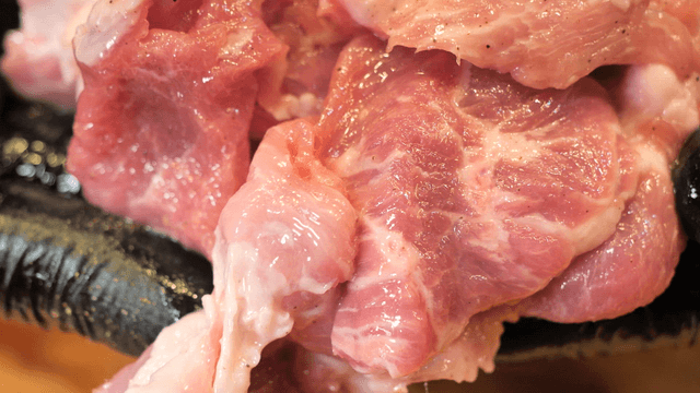 Raw pork pieces on black gloves