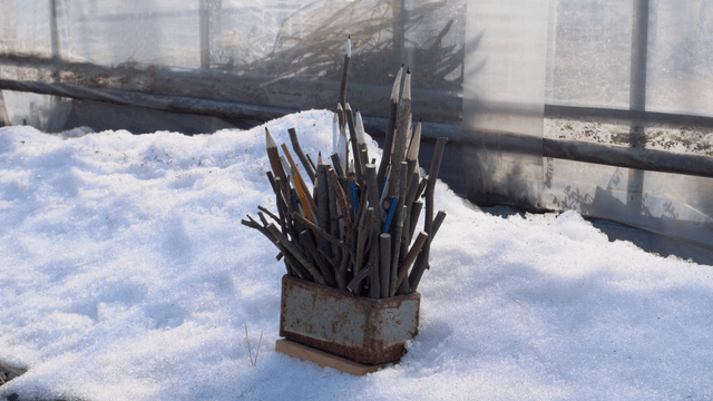 Wooden pencil sculpture placed on snow-covered ground