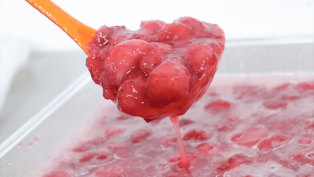 Strawberries marinated in sugar scooped with a ladle