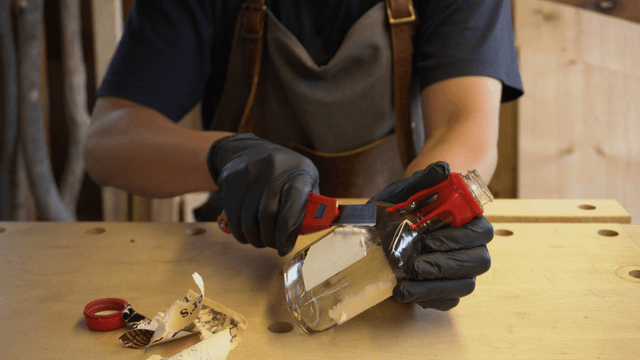 Person removing label from a glass bottle