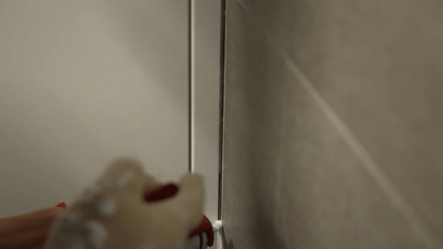 Worker applying sealant to wall corner