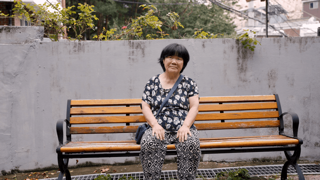 An elderly woman sitting on a bench outdoors