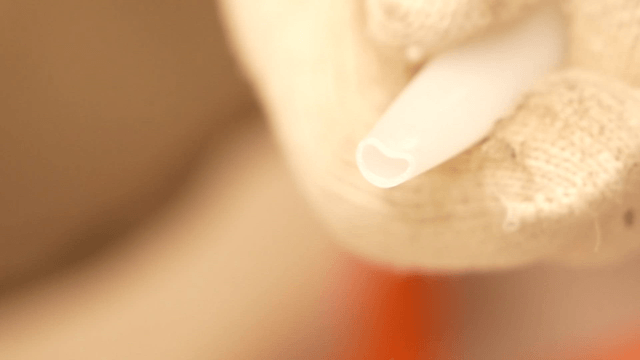 Close-up of gloved hand holding silicone gun nozzle