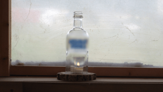 Candle in a bottle on a window frame