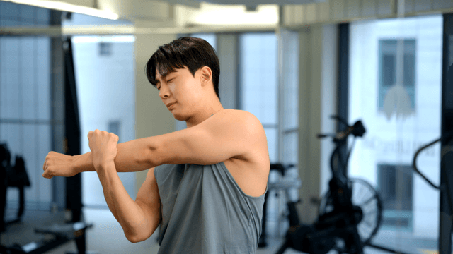 Young man stretching arms in a modern gym