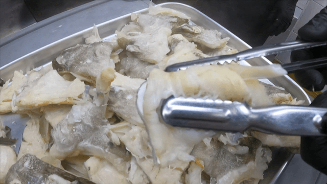 Boiled boneless cod pieces pressed with tongs