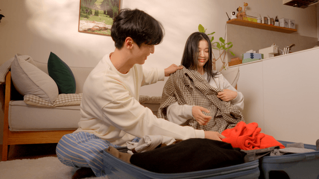 Couple organizing home with suitcase in cozy living room