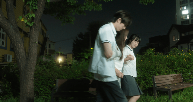 Three friends getting up from a bench at night