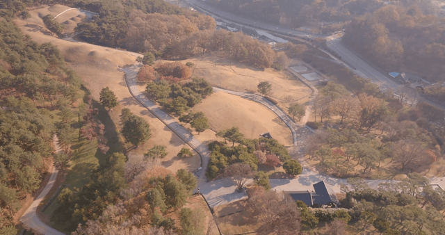 Traditional Korean building and ancient tomb surrounded by forest