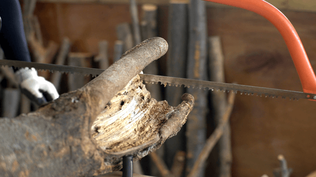 Carpenter cutting a log with a saw in workshop
