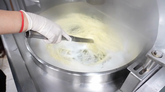 Noodles being stirred in a steaming pot