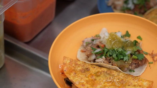 Tacos being prepared with green salsa