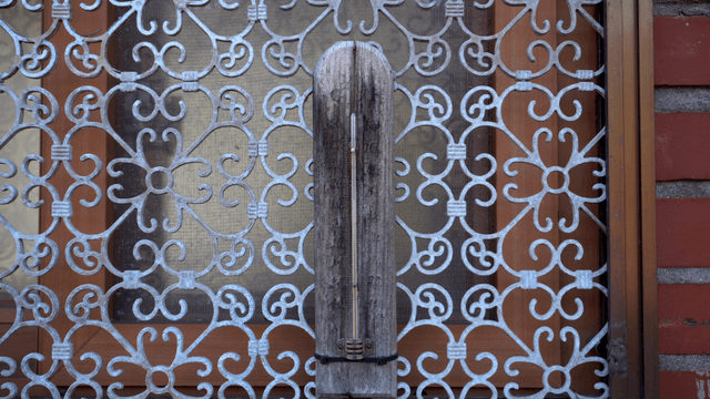 Wooden sculpture in front of a window with metal lattice