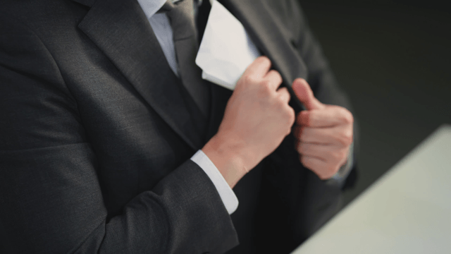 Person putting an envelope of cash into a pocket
