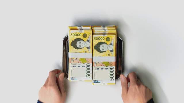 Hand receiving a tray with Korean currency on it