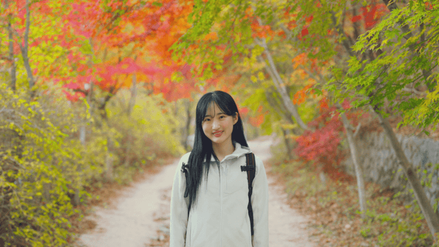 Young woman enjoying autumn maple forest trail