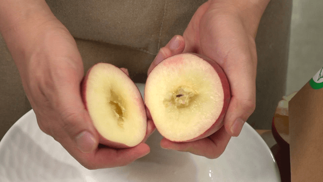 Hand slicing a peach in half