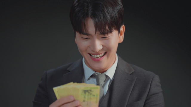 정장을 입은 남자가 돈을 보며 미소 짓는 모습