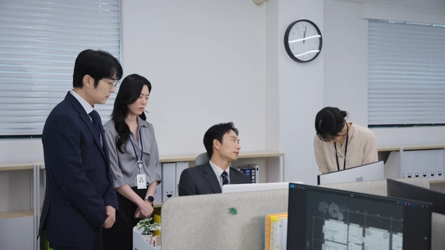 Office workers gathered around a desk, being scolded