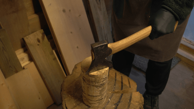 Person chopping wood with an axe in workshop