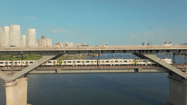 A subway and cars on a bridge over a river