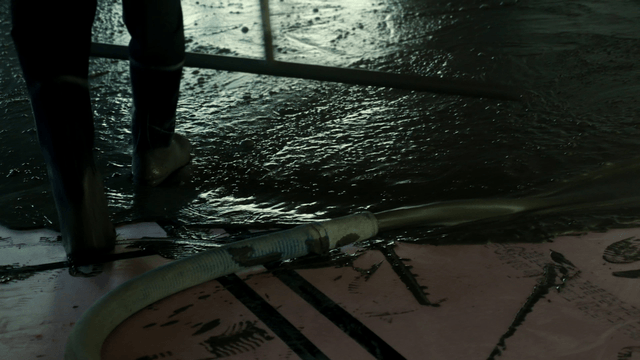 Worker spreading concrete indoors