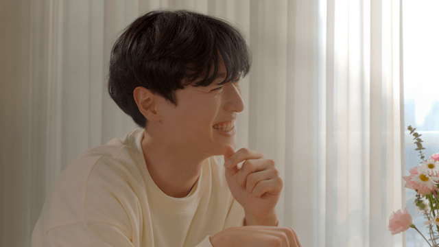 Man smiling by window with flowers