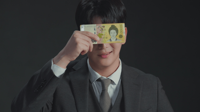 Man smiling with his eyes covered by money