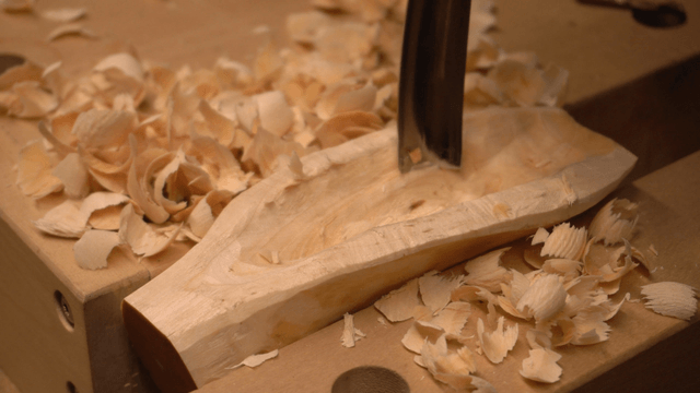 Woodcraft artisan carving grooves into wood with a chisel in workshop