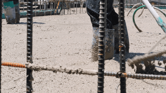 Worker smoothing wet concrete on a site