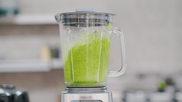 Blending green vegetables in a blender
