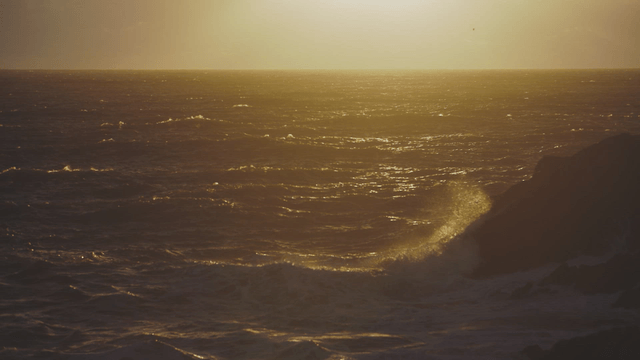 Sunset over the ocean with waves crashing