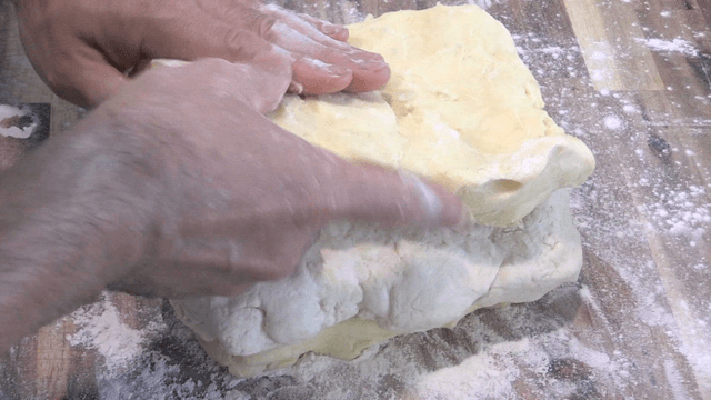 밀가루를 뿌린 조리대에서 반죽을 쌓는 제빵사 손