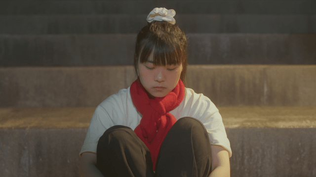 Girl sitting on the steps wearing a red scarf and looking at ice cream